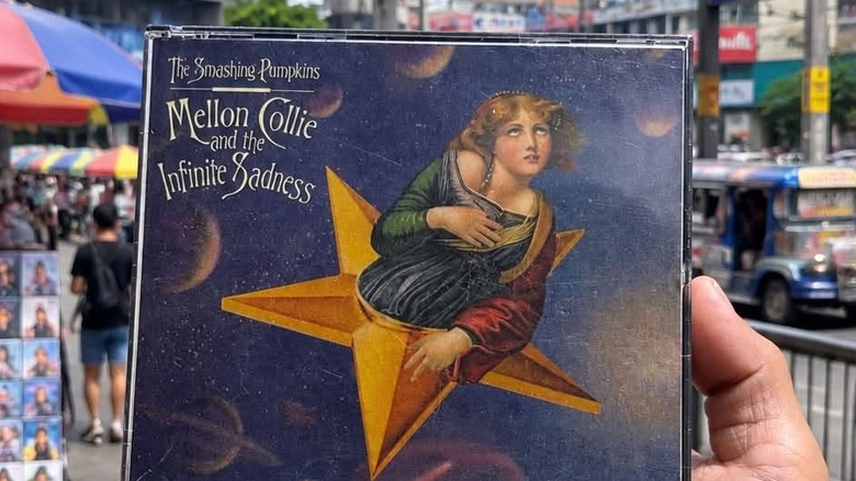 A hand holding a CD version of The Smashing Pumpokins' album "Mellon Collie And The Infinite Sadness"