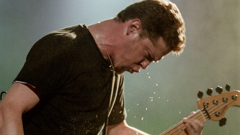 Jason Newsted dripping sweat while playing bass on stage
