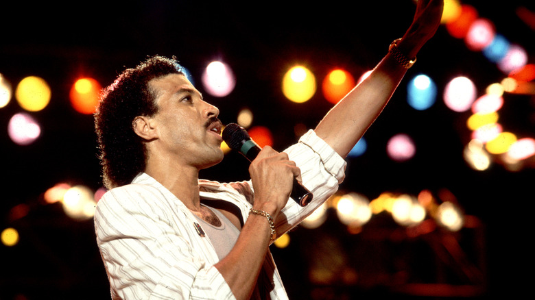 Lionel Richie performing on stage and holding a microphone
