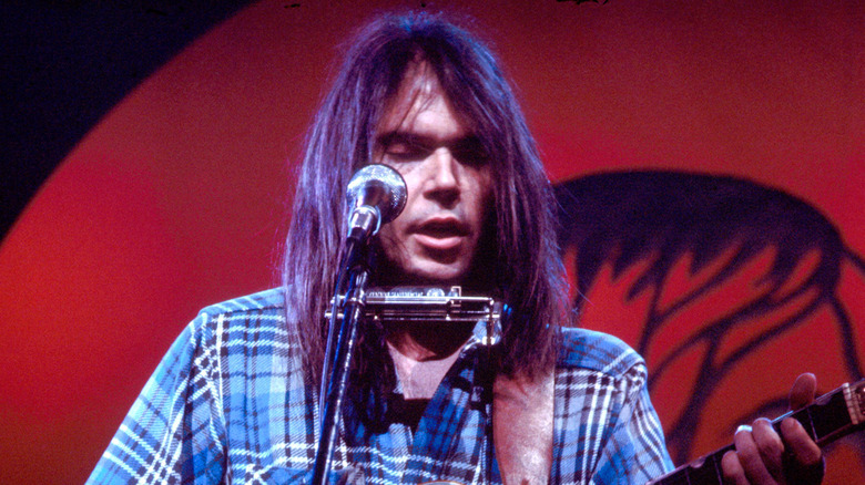 Neil Young with a harmonica and guitar