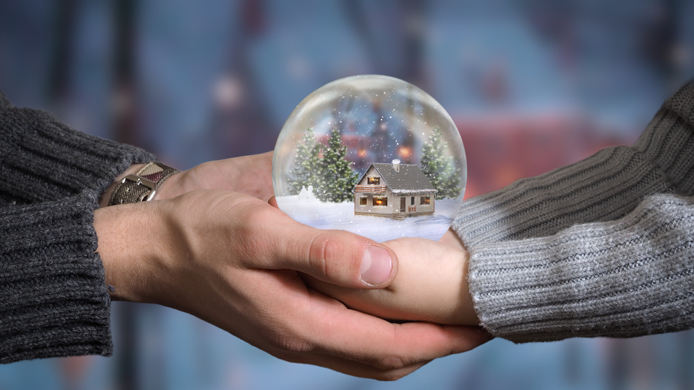 Adult hands and child hands holding a snow globe