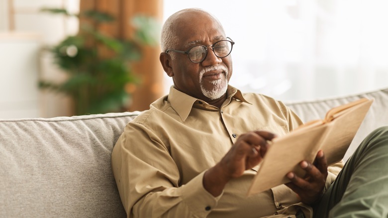 Man reading on a couch wearing glasses
