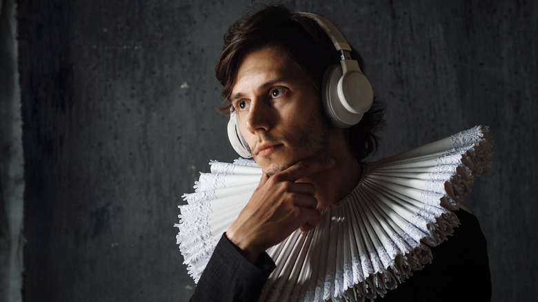 A man in historical dress with a ruff wearing headphones