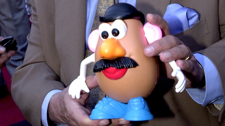 man in suit holds Mr. Potato Head