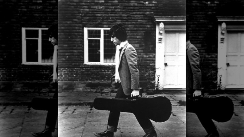 Jeff Beck carries guitar down road