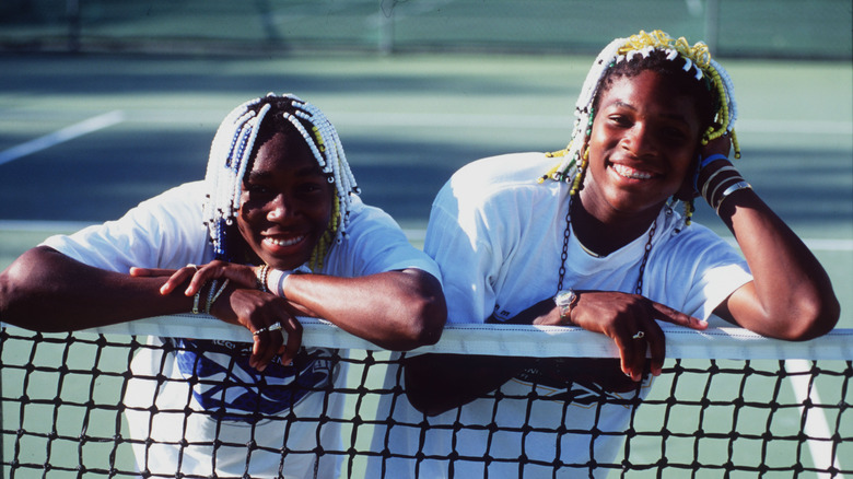 Young Serena and Venus lean on net