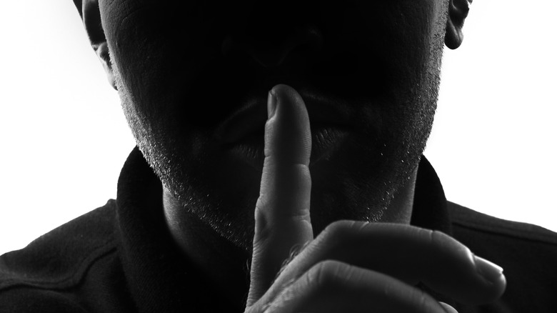 figure with finger over lips