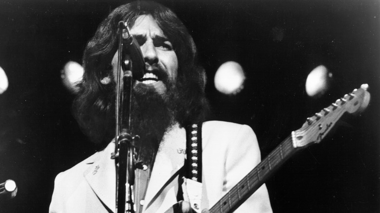 George Harrison in 1970s singing and playing guitar on stage