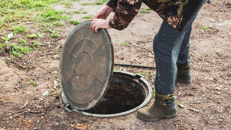 man opening a septic tank hatch