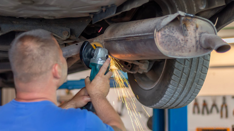man fixing auto muffler