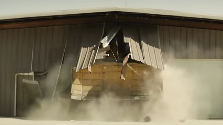 screenshot from tread documentary of bulldozer breaking out of shed