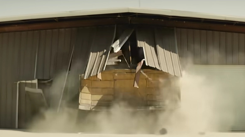 screenshot from tread documentary of bulldozer breaking out of shed