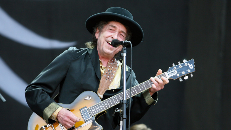 Bob Dylan onstage with guitar in black outfit in 2009