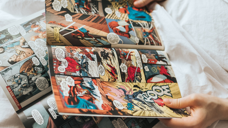 hands holding spider man comic open