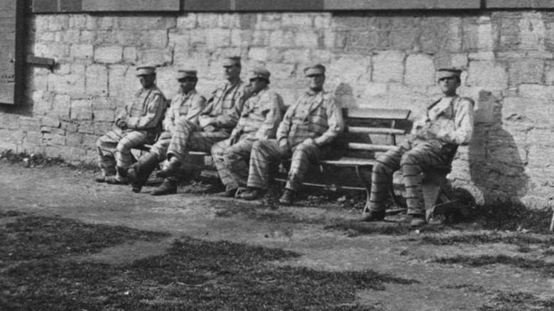 Prisoners sitting on a bench outside Auburn Prison in New York