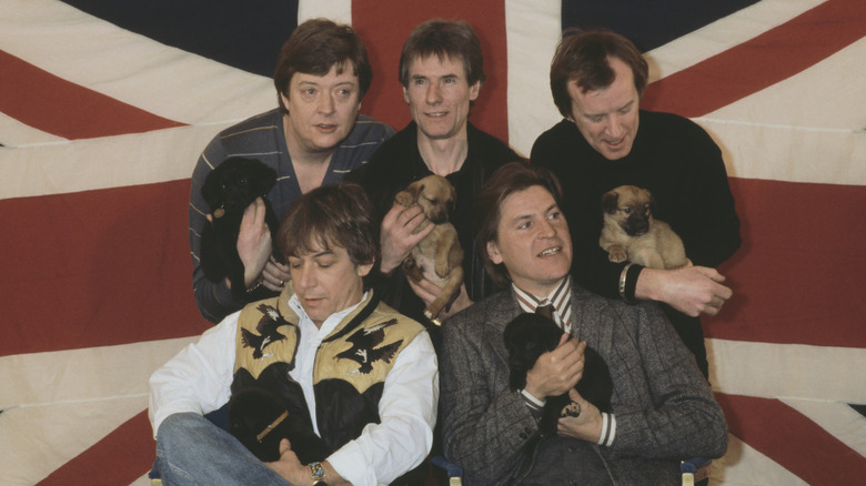 The original line-up of the Animals posing with puppies in front of a British flag.