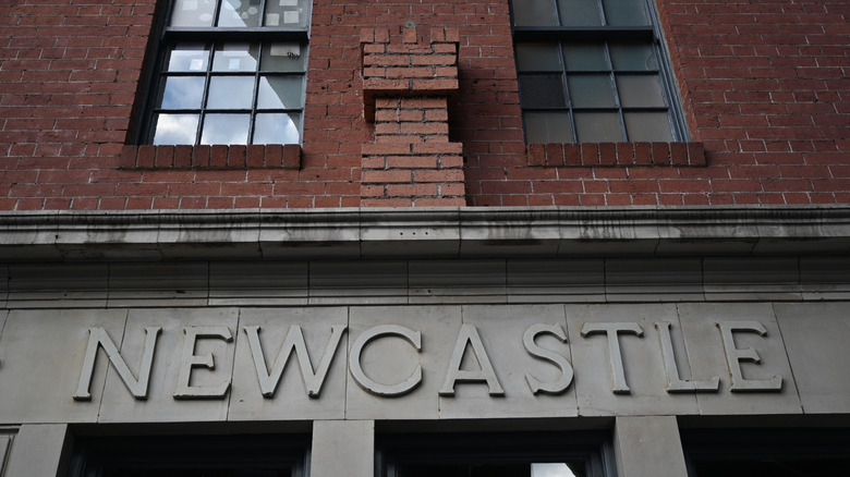 A brick wall above an entryway that says "Newcastle."