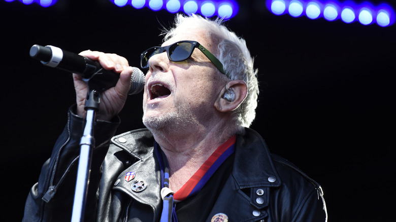 Eric Burdon singing on stage, wearing a black leather jacket.