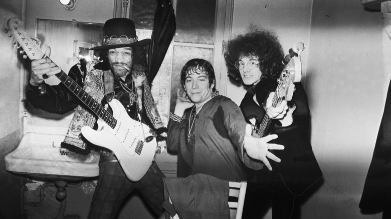 Left to right, Jimi Hendrix, Eric Burdon, and Mitch Mitchell posing for a camera.