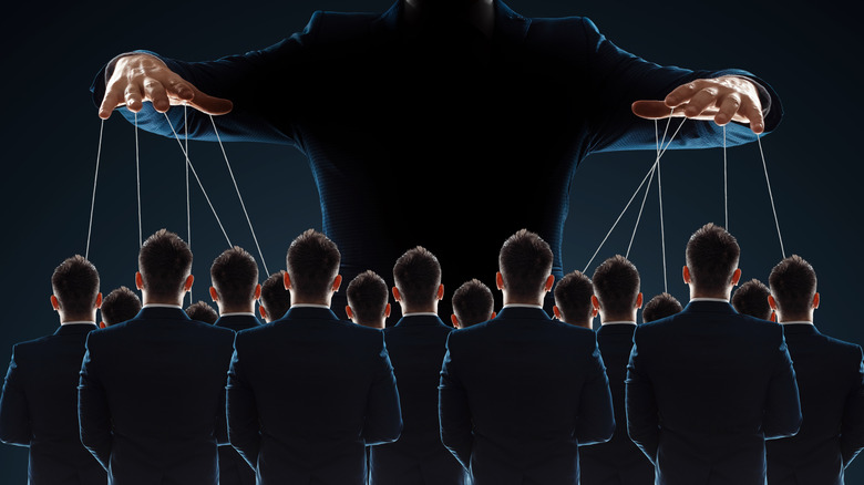 Puppet master controlling men suits
