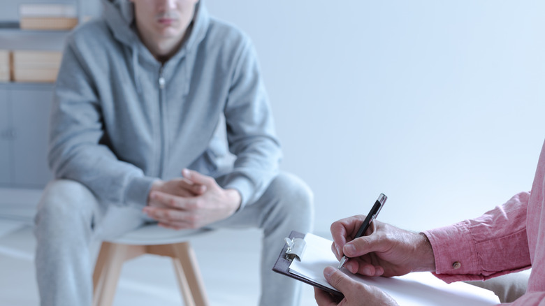 In the front hands of a therapy specialist taking notes during an individual meeting