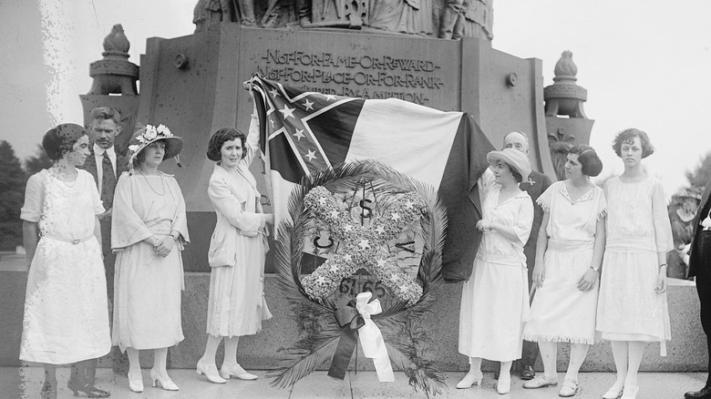 united daughters of the confederacy laying wreath and flag at monument