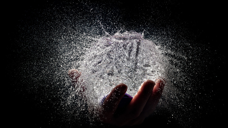 Hand holding exploding water balloon