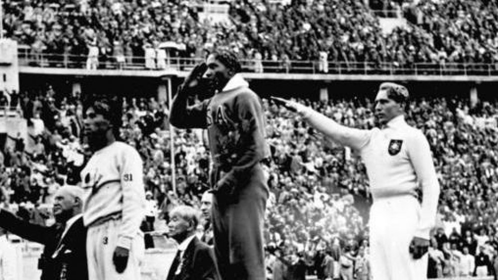 Jesse Owens on the podium after winning the long jump at the 1936 Summer Olympics. Naoto Tajima is in bronze medal position and Lutz Long won silver