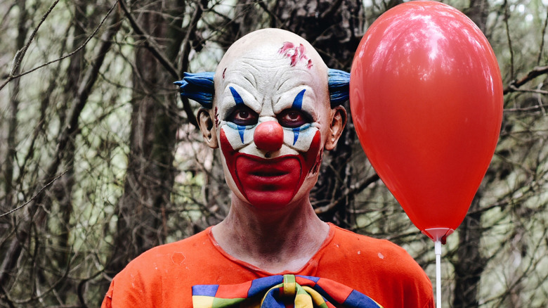 scary clown in the woods with balloon