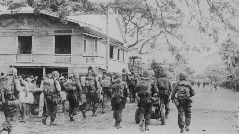 118th glider regiment marching through village on Luzon