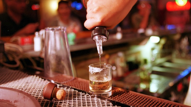 Hand pouring shot of tequilla