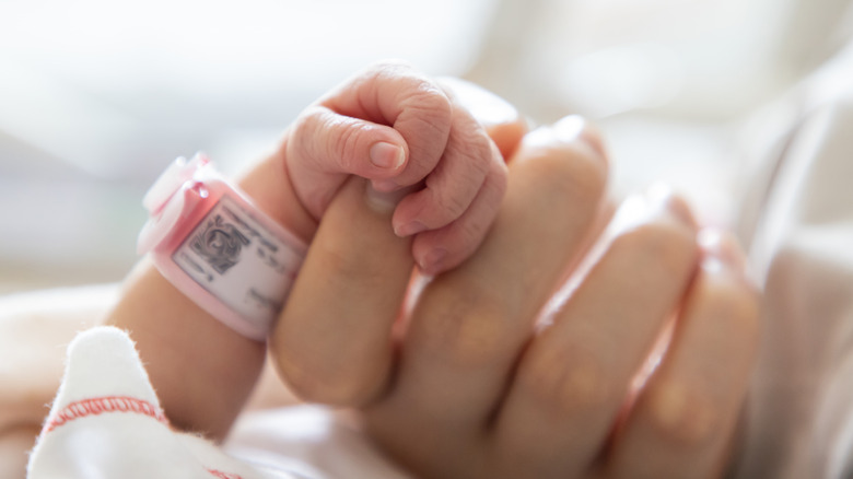 Baby gripping mother's finger