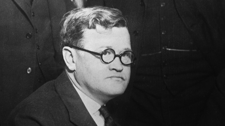 Leo Koretz glasses suit sat sullen