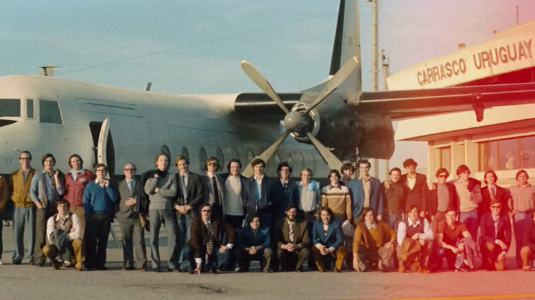 A team poses for a picture in front of a plane