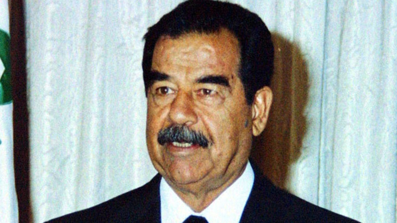 Saddam Hussein talking in suit