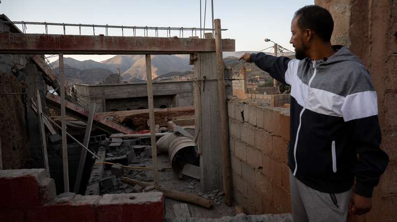 man pointing to the remains of his house