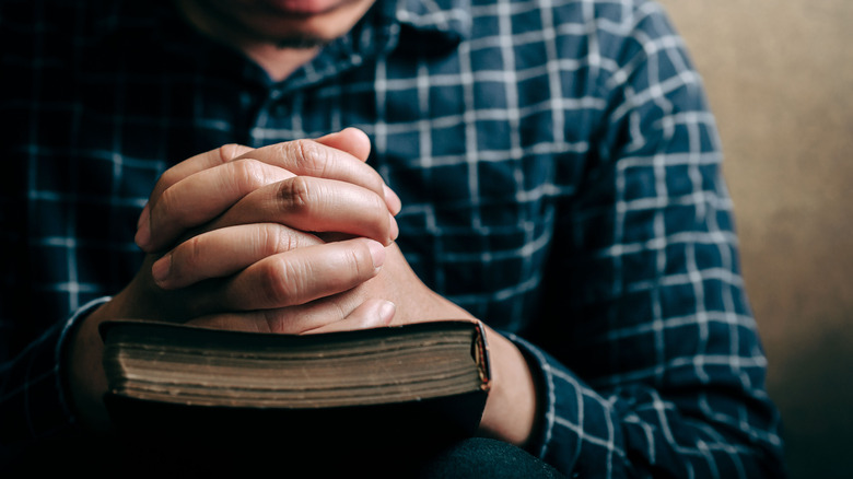 folded hands on a bible