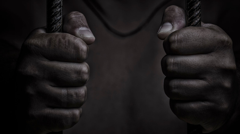 Hand of prisoner on jail bars
