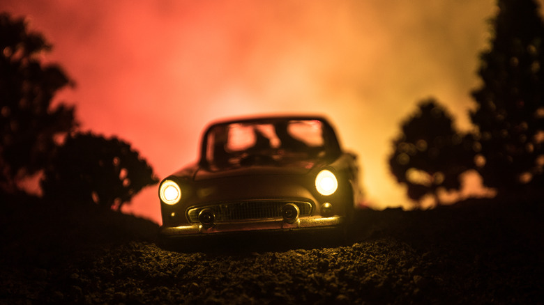 Car in eerie forest at sunset