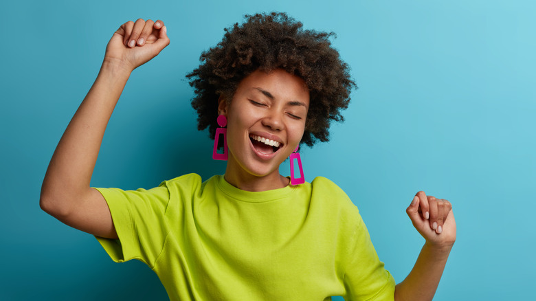 happy person dancing close up against blue backdrop