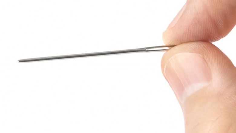 fingers holding sewing needle