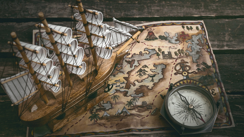 ship, map, and compass on wooden desk