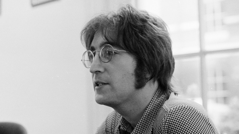 A black and white photo of John Lennon in a checkered shirt