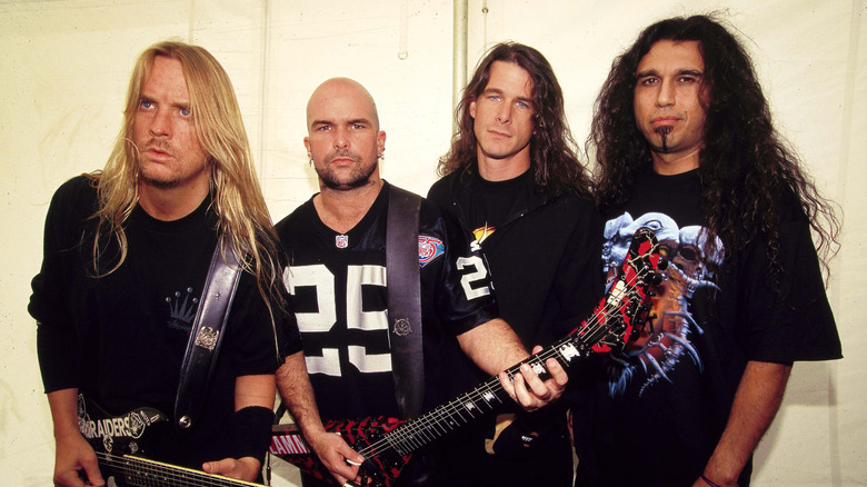 Members of Slayer line up together for a photo while two members hold guitars