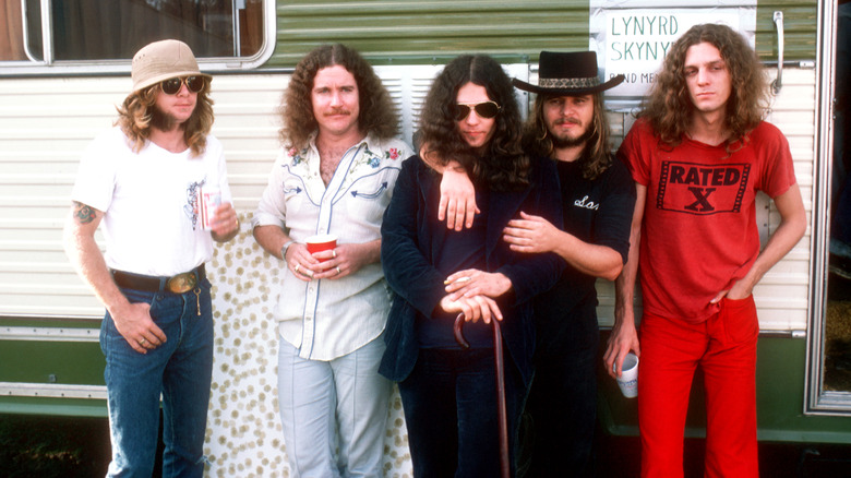 Members of Lynyrd Skynyrd stand together in front of a green and white trailer