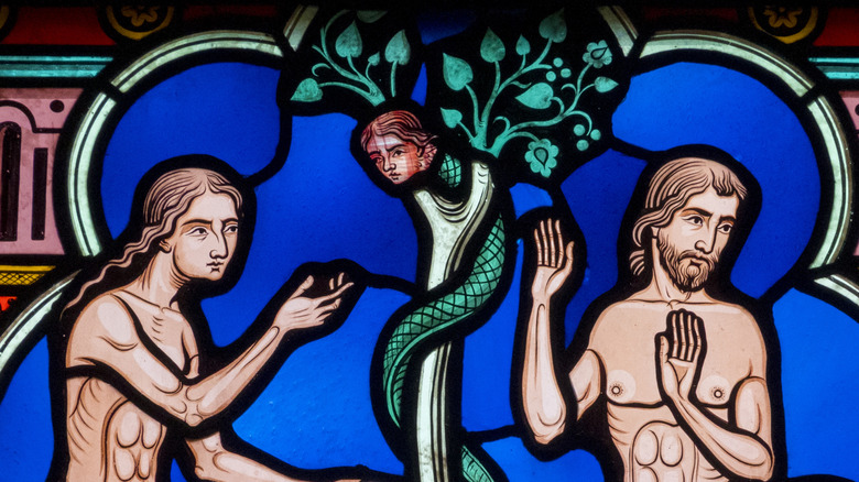 Stained glass of Adam and Eve in paradise tempted by the snake, Montfaucon, France