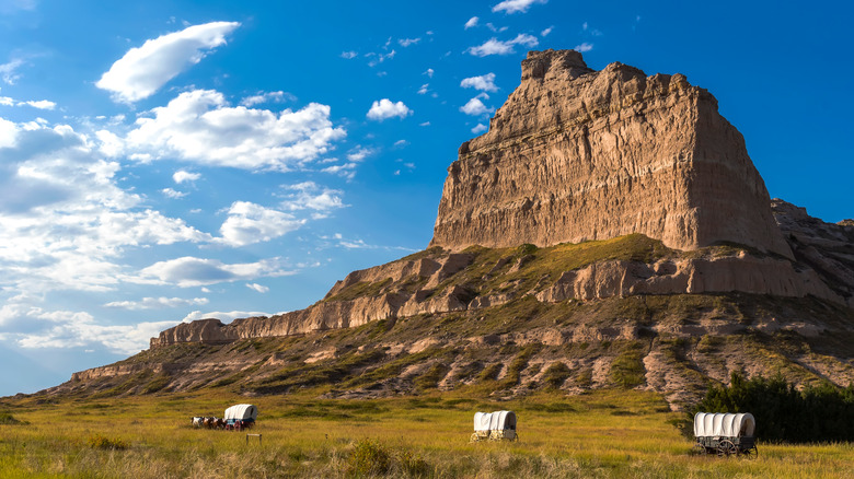 Wagon caravan traversing rocky grassland 