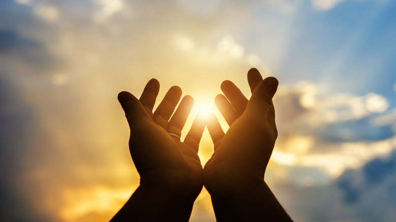Hands reaching towards sun