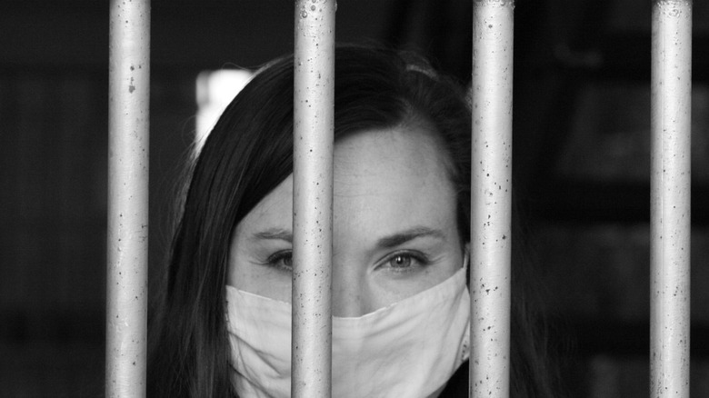 woman with a mask behind bars