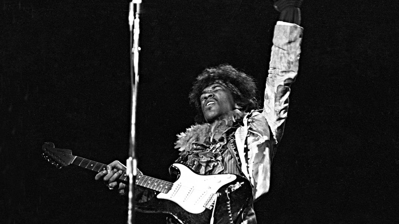 Jimi Hendrix onstage with hand raised to the sky.